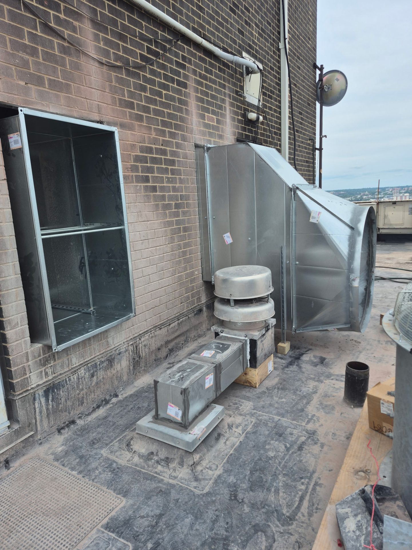 Rooftop sheet metal — wall louver, square-to-round transition, and roof caps on a commercial job